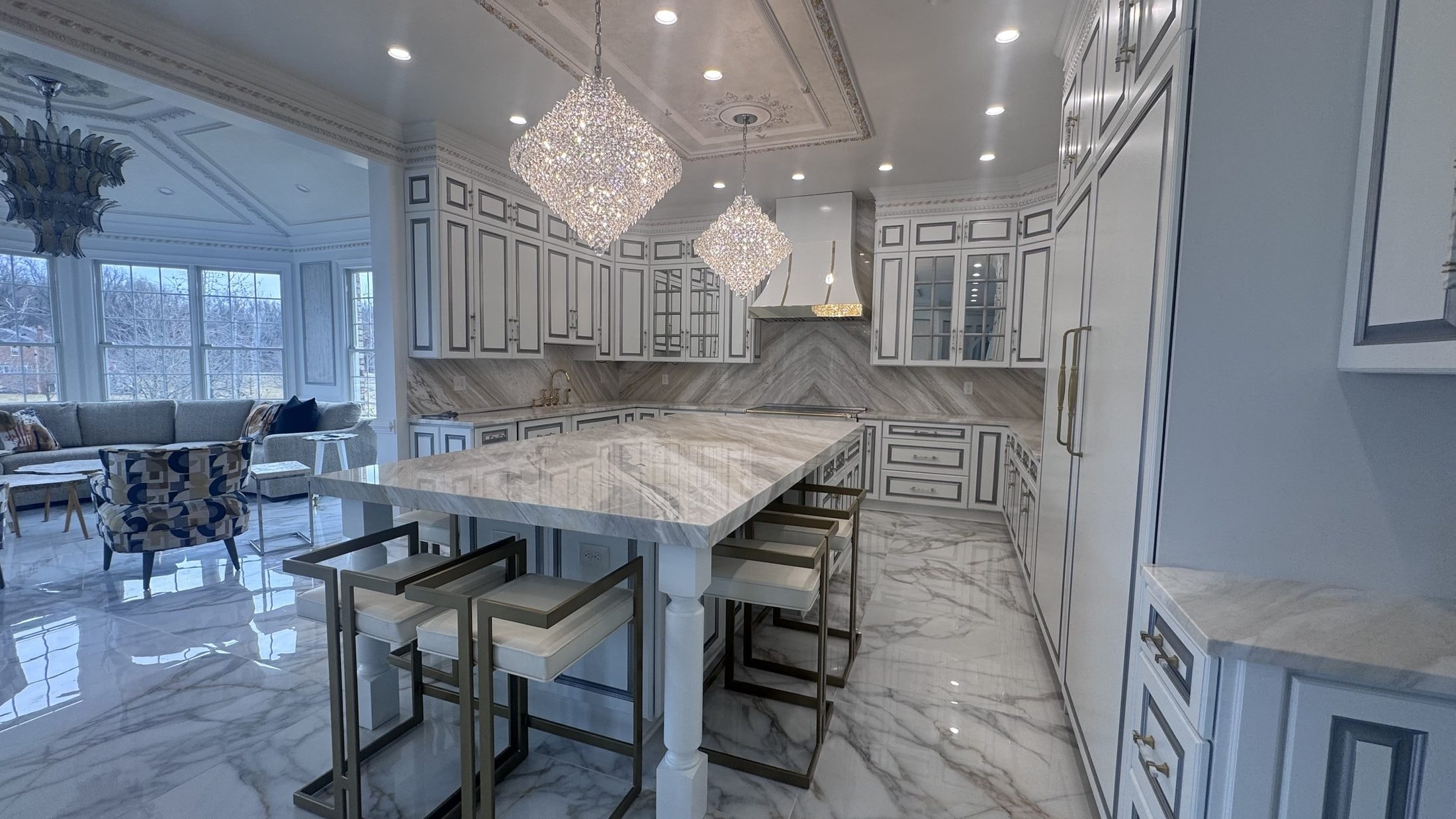 Kitchen with marble island and crystal pendants, designed by John Hashempour